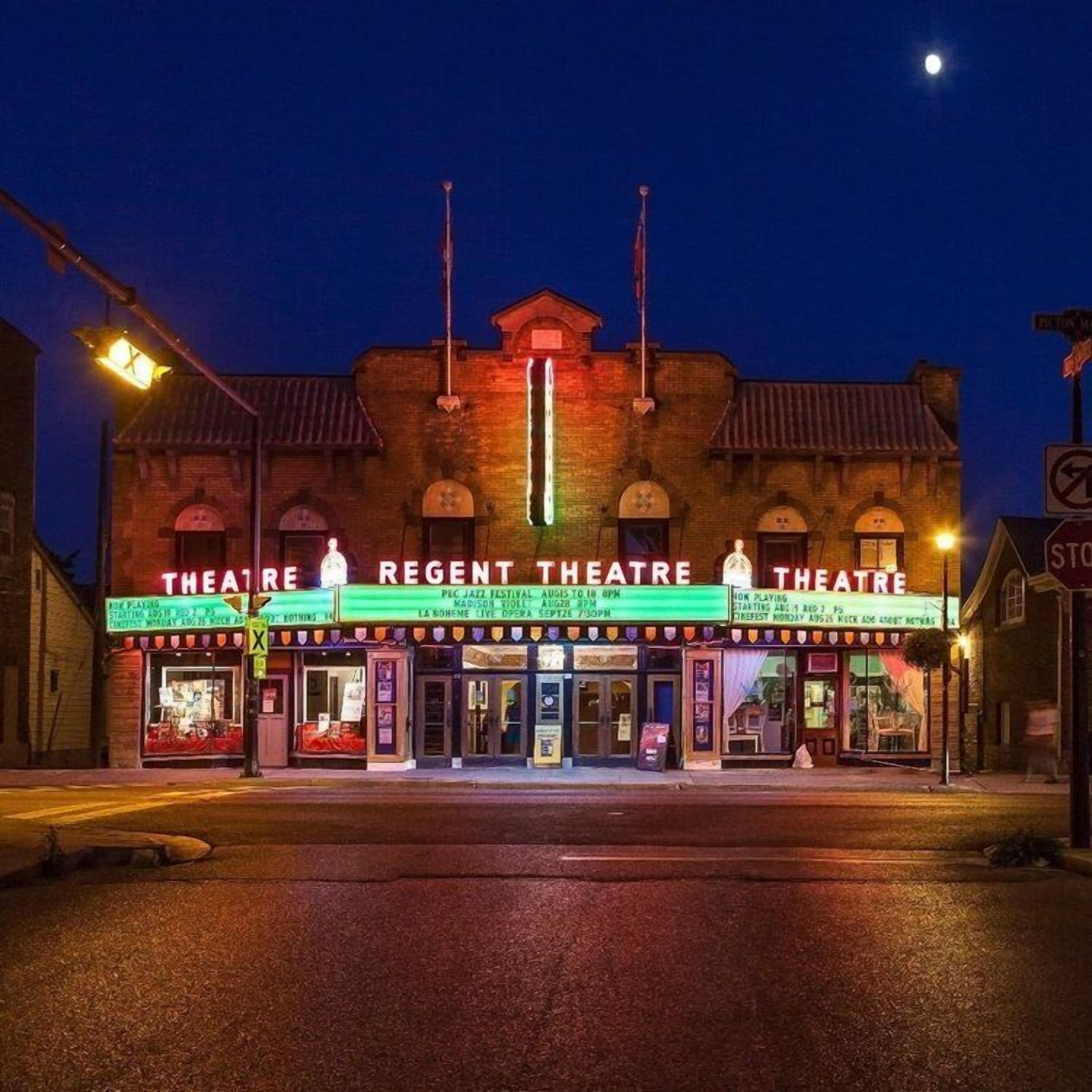 Een Regency Theater gebouw met een lichtreclamebord waarop verschillende voorstellingen staan vermeld.