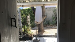 A doorway leading to a covered outdoor area with a tiled floor, a tree, and a white umbrella. - Maisonnette33m2 plage à 250m (Six-Fours-les-Plages)