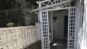 A covered outdoor area with a tiled floor, a brick wall, and a white decorative fence. - Maisonnette33m2 plage à 250m (Six-Fours-les-Plages)