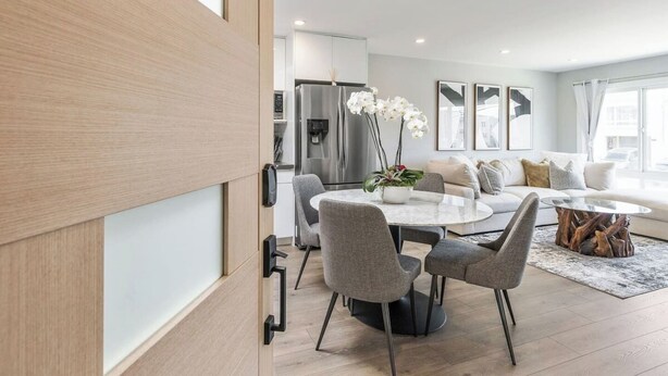 A modern living room with a round dining table, grey upholstered chairs, a white sofa, and a coffee table. - Luxury 7BR Home Near SFO w/Parking (Daly City)