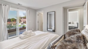 A hotel room with a bed, a large mirror, and a view of the outdoor area. - Luxury 7BR Home Near SFO w/Parking (Daly City)