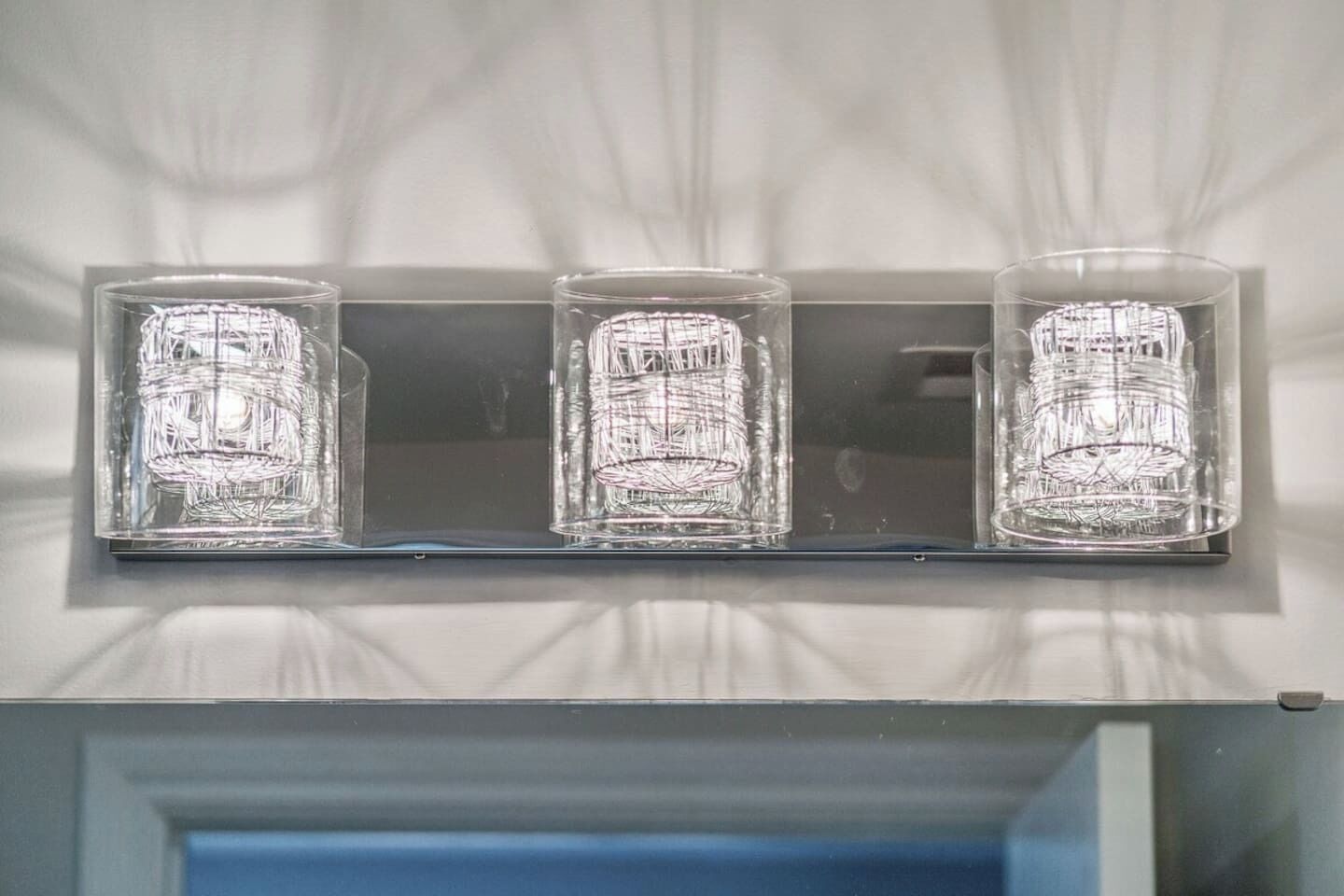 Eine Wandleuchte mit drei klaren Glasscheiben.