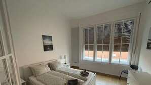 A bedroom with a bed, bedside tables, a lamp, a chair, a dresser, and a window with blinds. - CITY CENTER 1, Fantastic apartment in the city center! (Budapest)