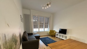 A living room with a sofa, a small round table, a TV, and a window with blinds. - CITY CENTER 1, Fantastic apartment in the city center! (Budapest)