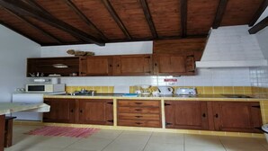 Eine Küche mit Holzausstattung, einer Mikrowelle, einer Kaffeemaschine und einer gefliesten Spritzschutzwand.