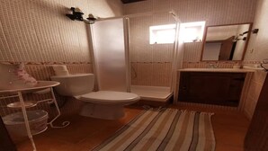 Ein Badezimmer mit Toilette, Dusche, Waschbecken und einem kleinen Spiegel.