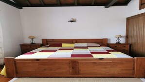 Ein hölzernes Bett mit einer Steude, zwei Nachttische mit Lampen und ein Holzschrank.