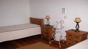 Ein Schlafzimmer mit einem Einzelbett, zwei Nachttischen mit Lampen, einem kleinen weißen Schrank und einem Wandregal mit Spiegel und Medikamentenschrank.
