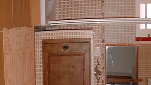 Ein Zimmer mit Holzboden, einer gefliesten Wand und einer Tür mit Griff.