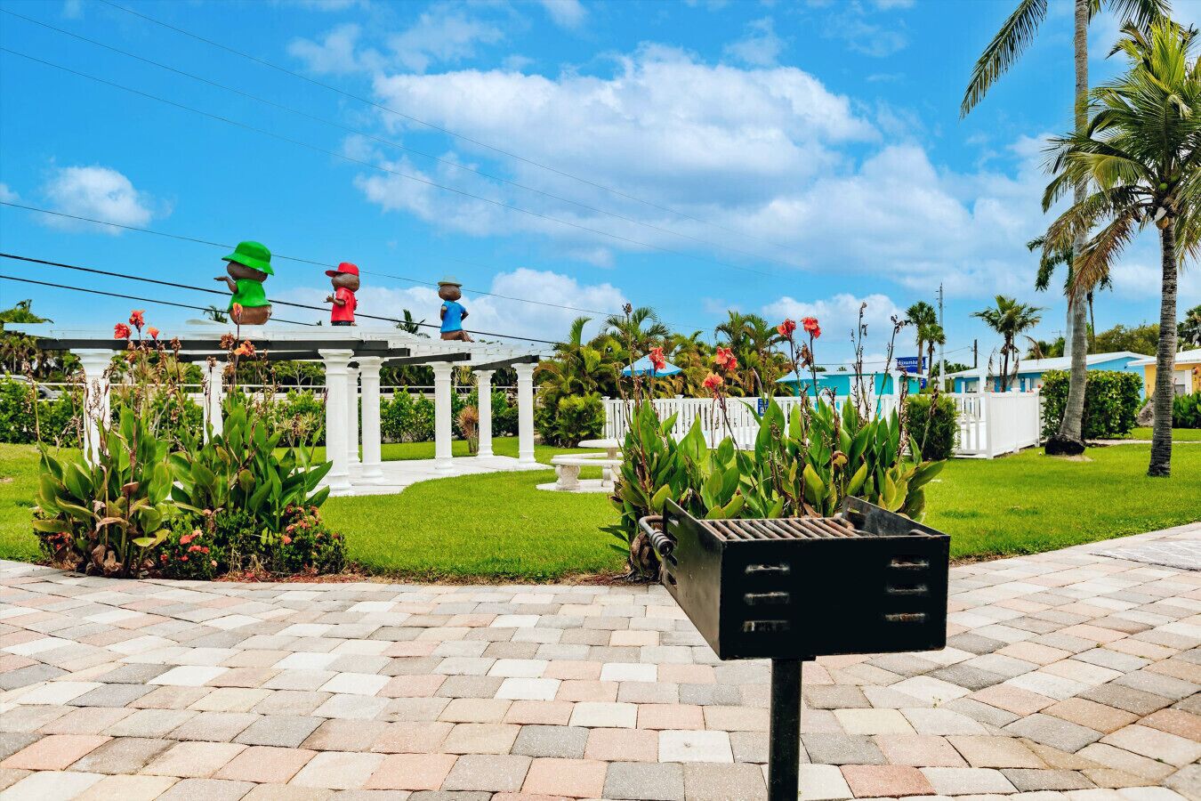 A gazebo with a white column structure, surrounded by well-maintained grass and plants.