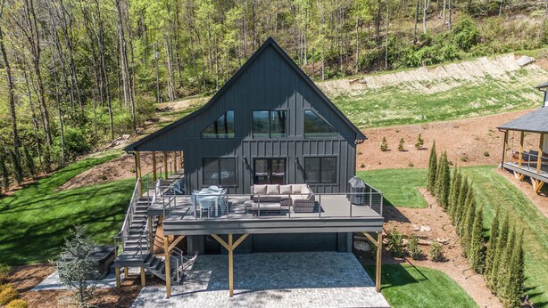 A modern two-story house with a large deck, surrounded by a well-maintained lawn and trees. - Luxury Mountain Escape (Hendersonville)