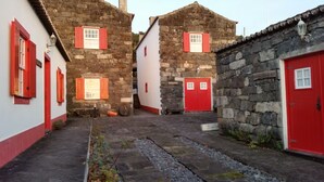 Une ruelle étroite bordée d’immeubles en pierre, de portes rouges et de fenêtres dotées de volets.