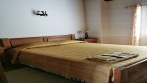 Un lit bien fait, avec une tête de lit en bois, une table de chevet avec une lampe et une fenêtre avec des rideaux.