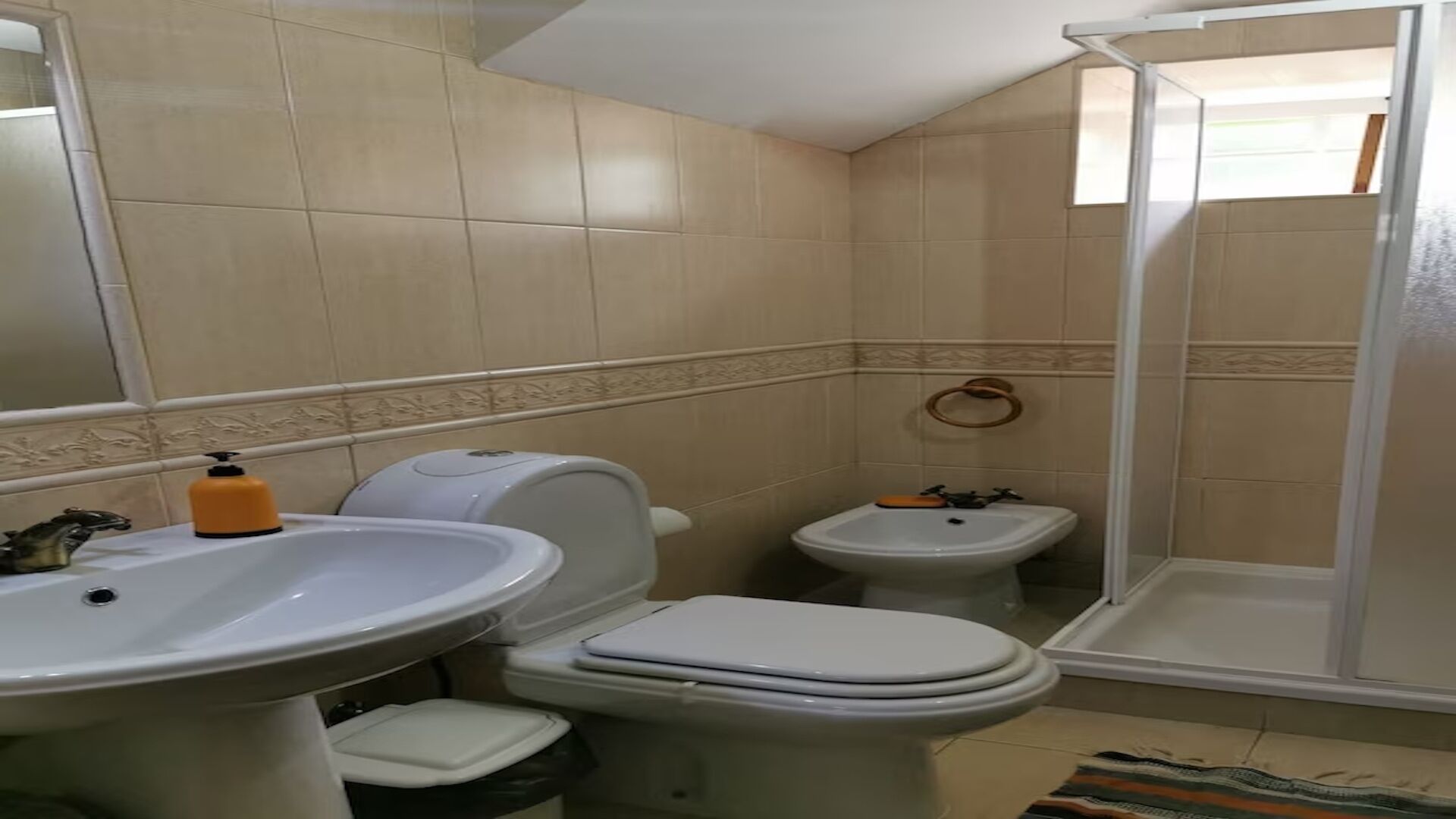 Ein Badezimmer mit zwei Toiletten, einem Waschbecken und einer Dusche.