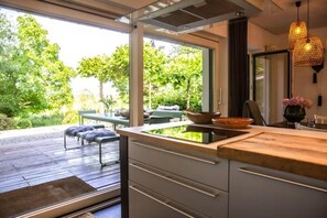 A modern kitchen with a large window, wooden deck, and outdoor seating area. - N7Quartier (Bad Münstereifel)