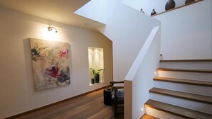 Ein modernes Interieur mit Holzboden, einer Treppe mit integrierter Beleuchtung und einem großen, abstrakten Gemälde an der Wand.