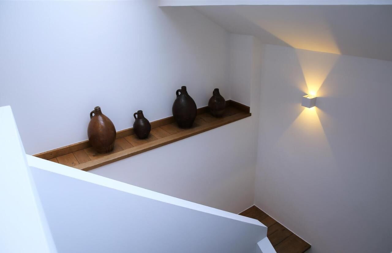 Una escalera con un estante de madera que sostiene varios jarrones de cerámica.