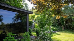 Ein moderner Außenbereich mit Terrasse, einer Pergola, üppigem Grün und einem gepflegten Rasen.