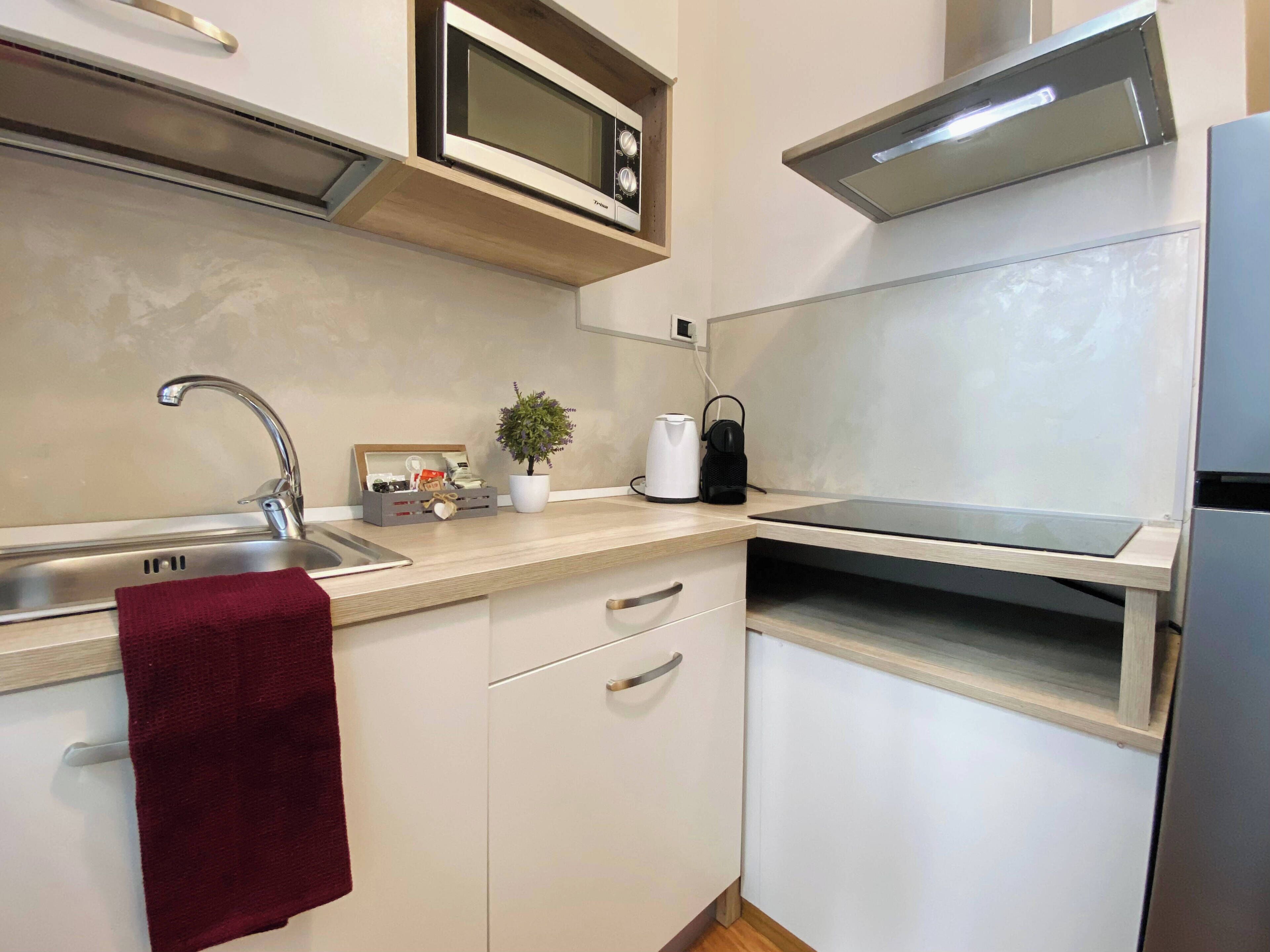 A modern kitchen with a stainless steel sink, a microwave, a kettle, and a toaster.