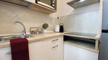 A modern kitchen with a stainless steel sink, a microwave, a kettle, and a toaster.