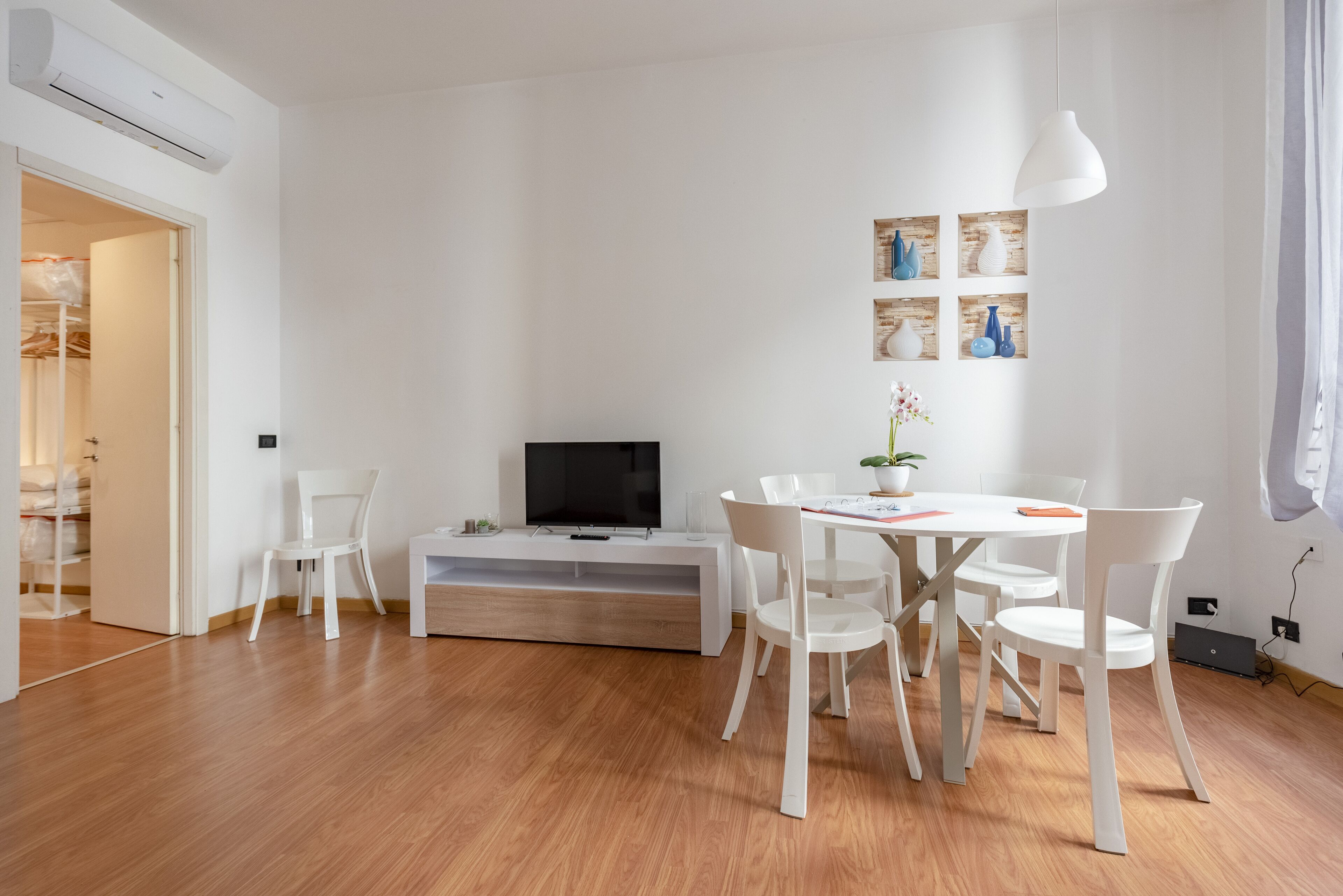 Un salon moderne doté d’un téléviseur à écran plat, de meubles blancs et d’un plancher en bois.