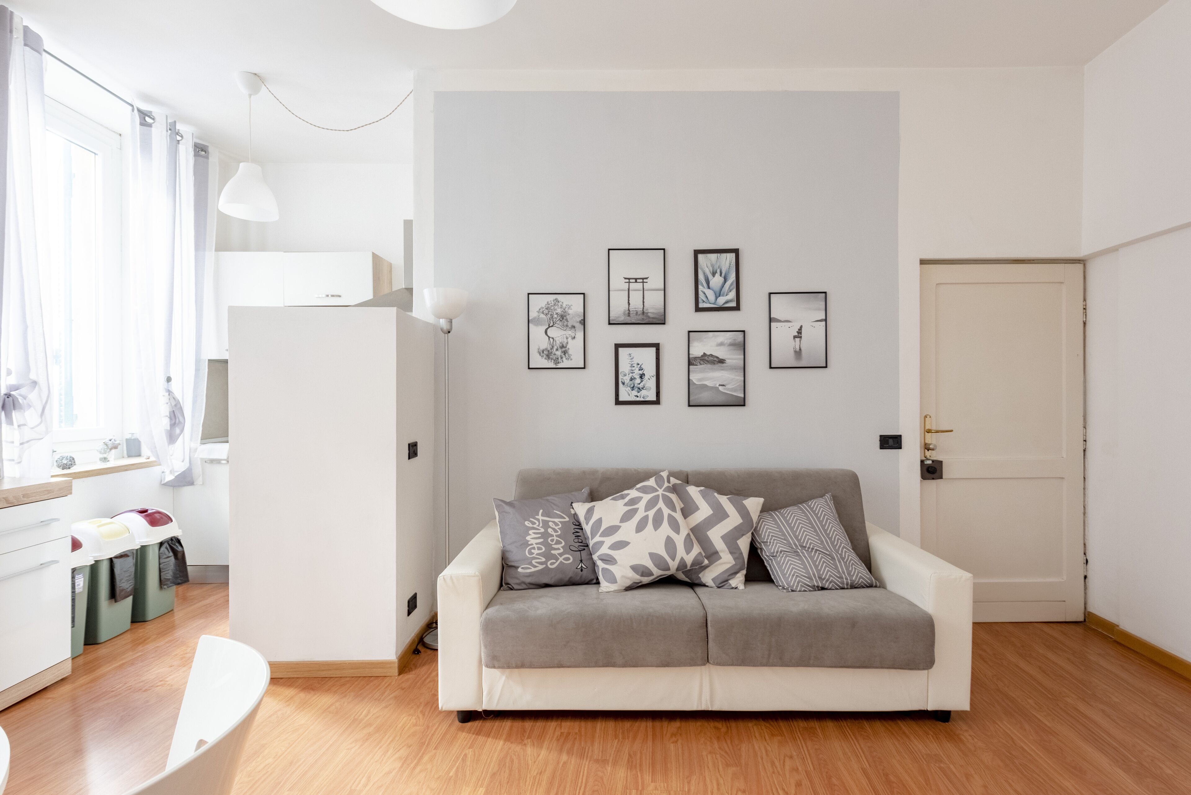A modern living room with a grey sofa, a white cabinet, and a wall with framed artwork.