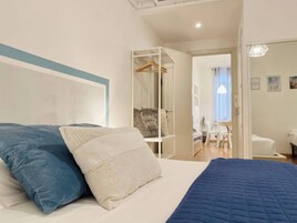 A bedroom with a bed, pillows, a wardrobe, and a desk.