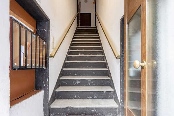 A staircase with black and white steps, a wooden door with a glass panel, and a metal railing on the left side.