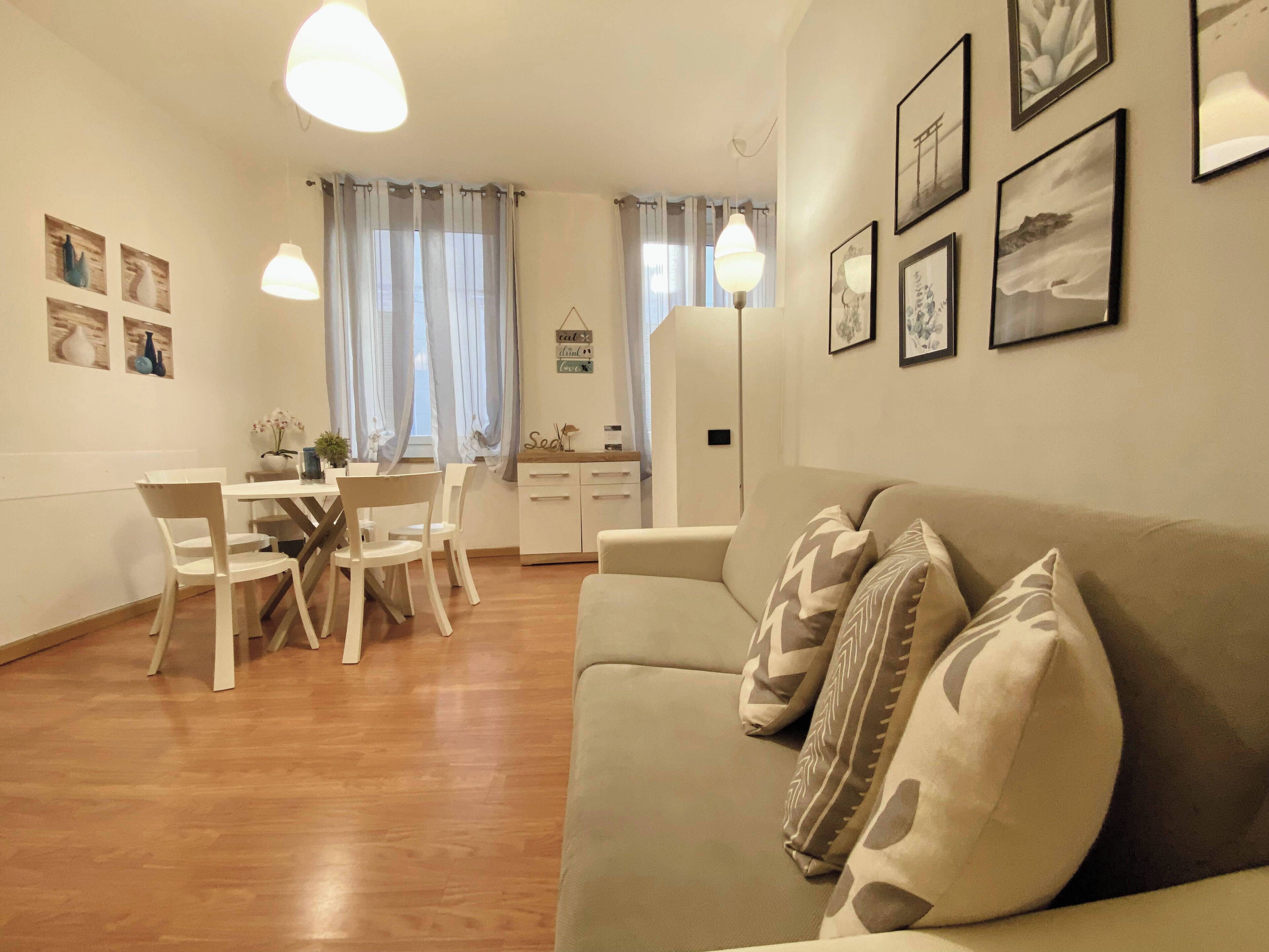 Una sala de estar acogedora con sofá, mesa de comedor, sillas y zona de cocina.