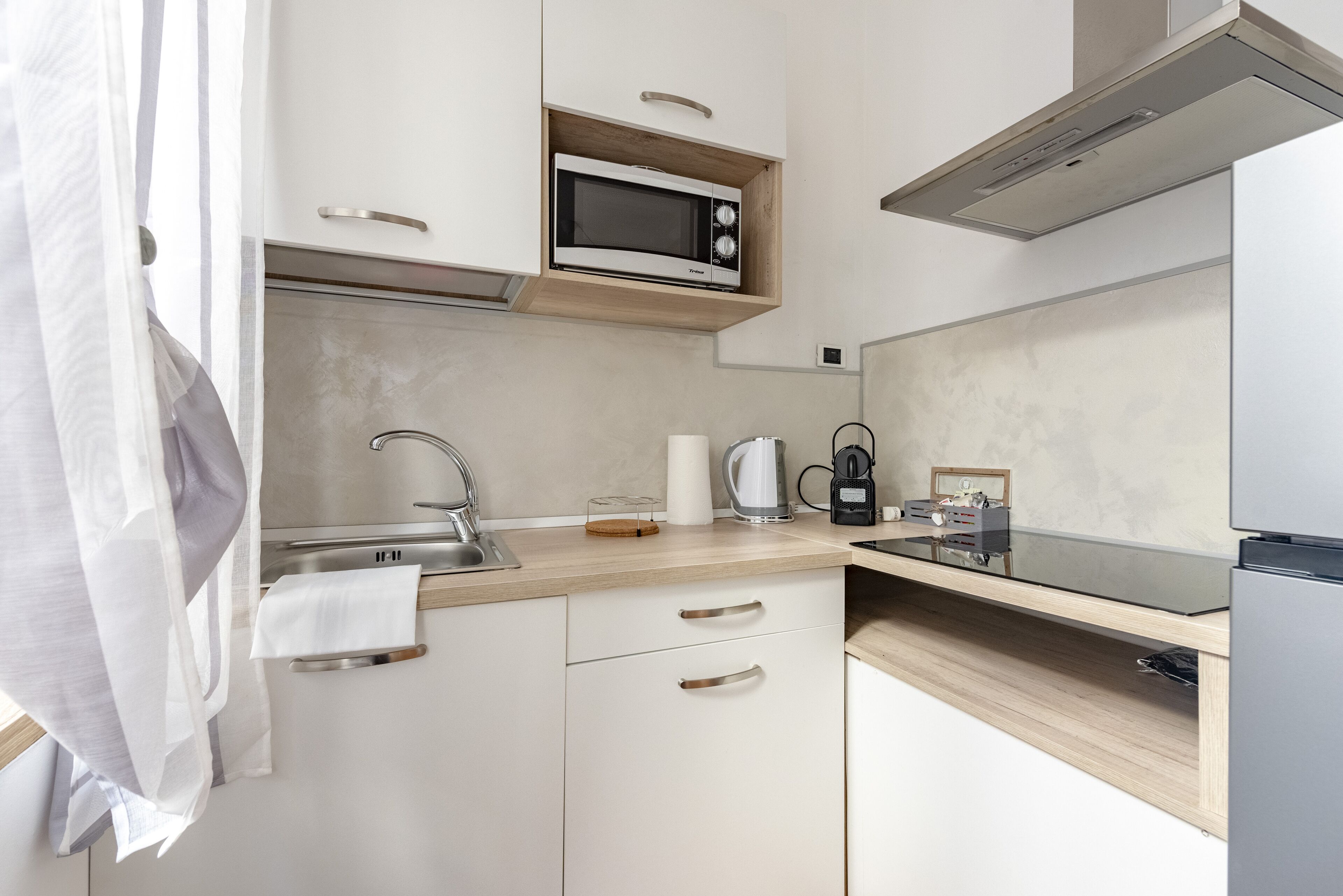 A modern kitchen with a microwave, coffee maker, and kettle on the counter.