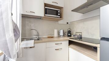A modern kitchen with a microwave, coffee maker, and kettle on the counter.