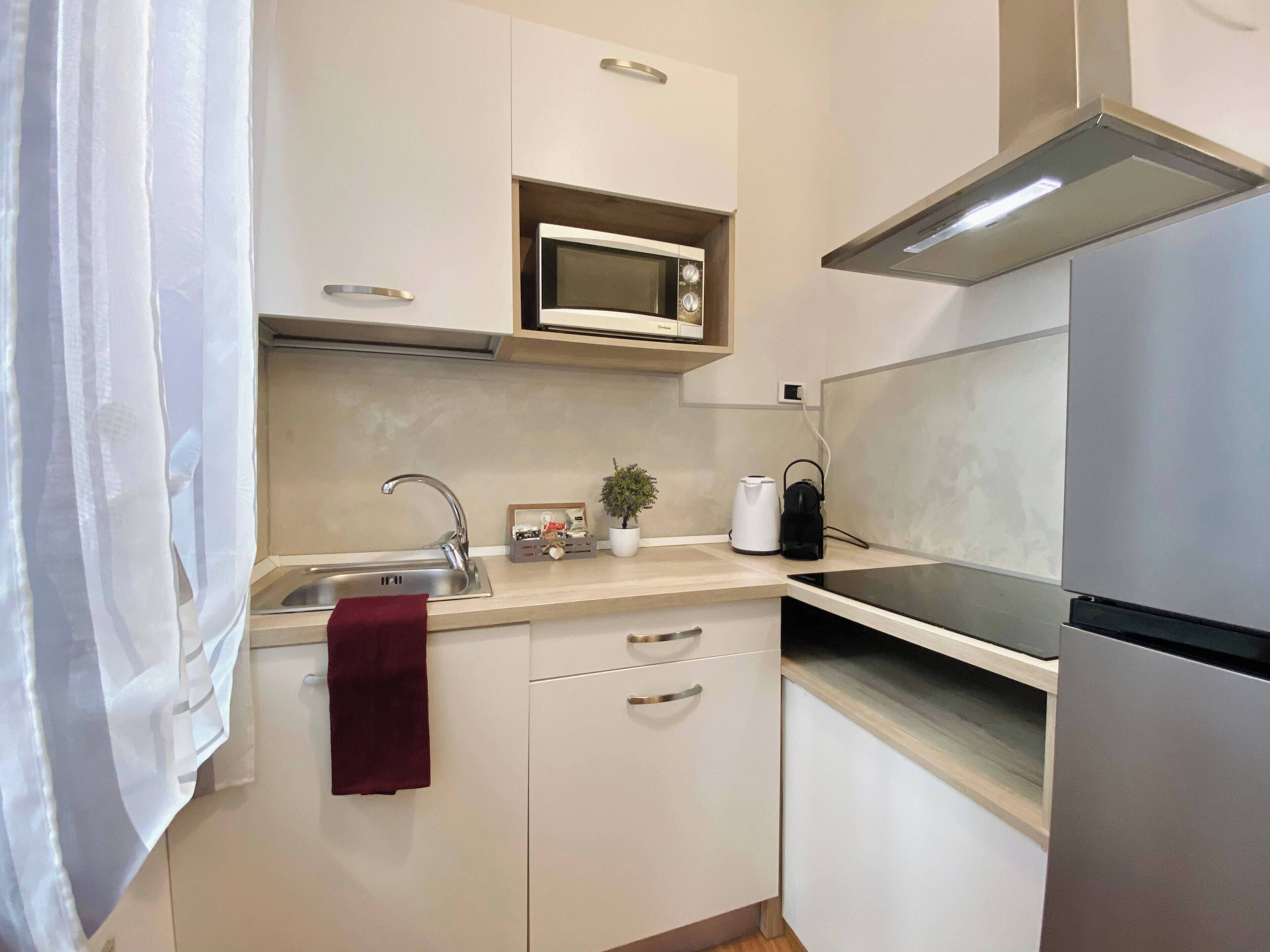 Een moderne keuken met een roestvrijstalen koelkast, een magnetron en een waterkoker op het aanrecht.