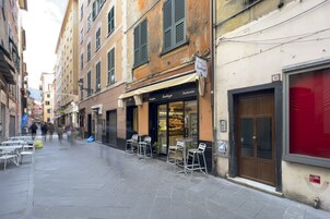 A narrow street with outdoor seating, a bakery, and a closed shop.