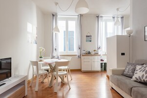 A modern living room with a TV, dining table, chairs, and a sofa.