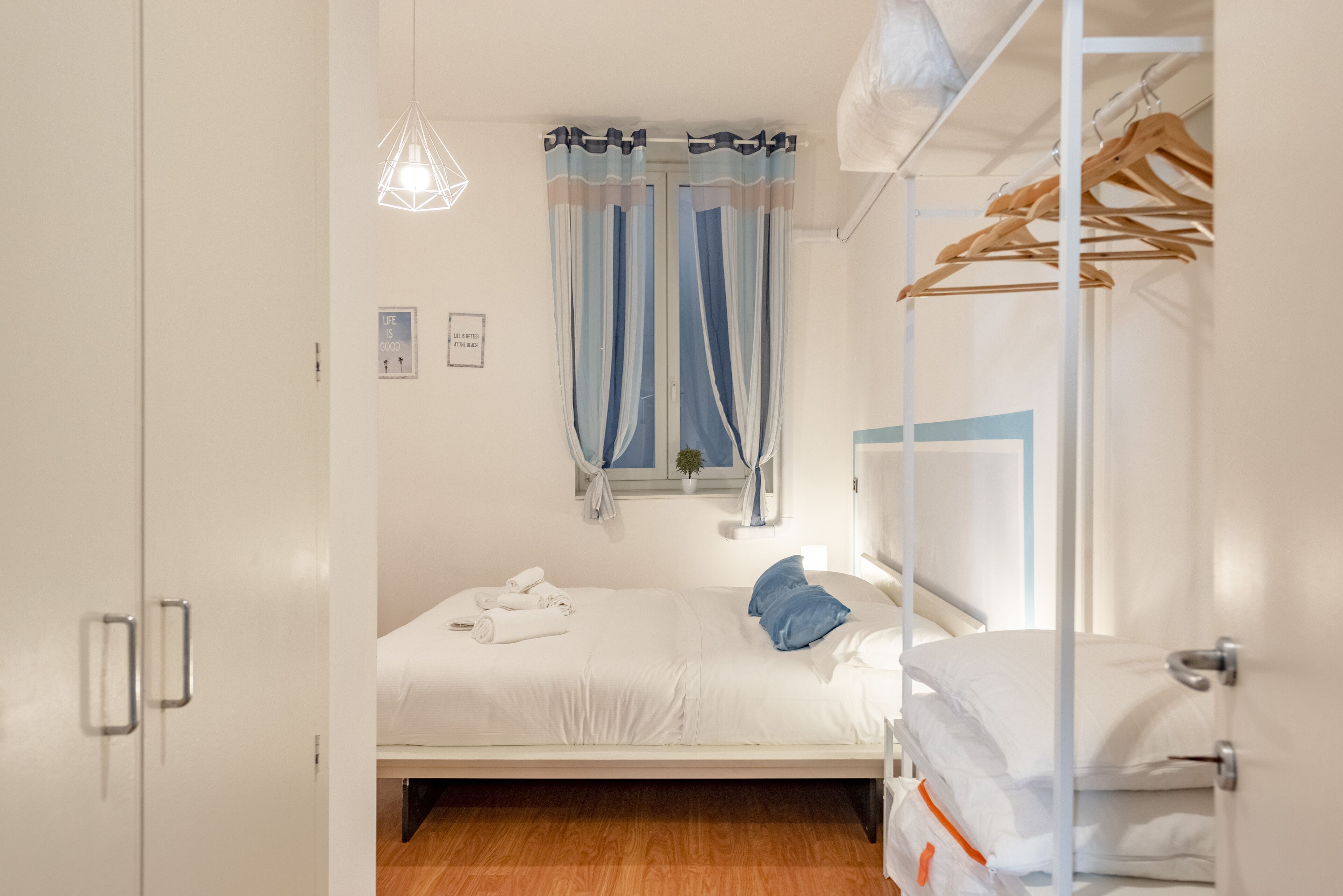 Une chambre à coucher avec un lit, une armoire, une lampe suspendue et une fenêtre avec des rideaux.