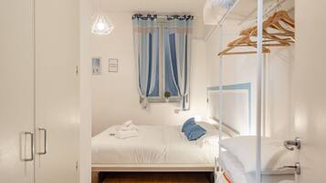 Une chambre à coucher avec un lit, une armoire, une lampe suspendue et une fenêtre avec des rideaux.