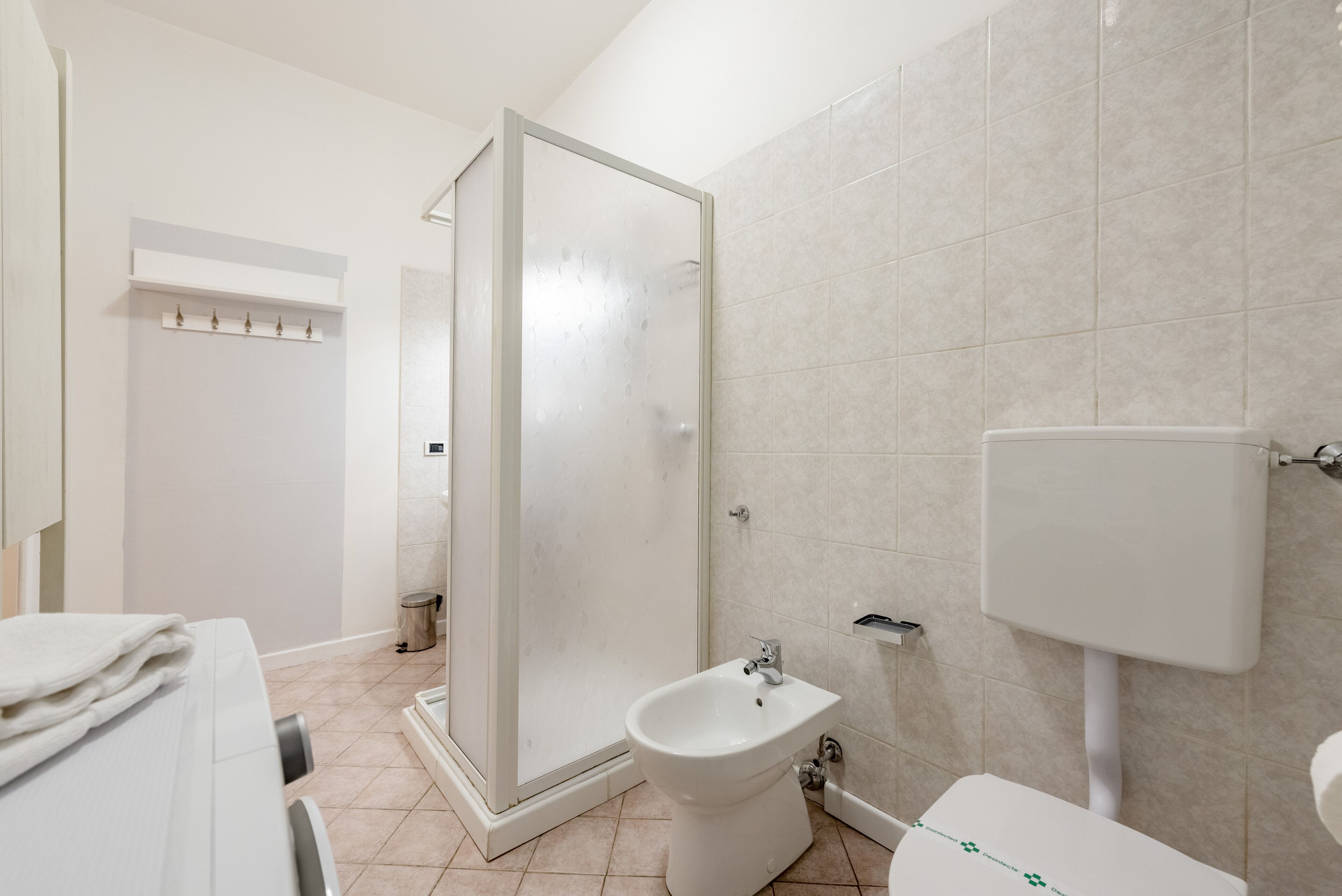Un baño con ducha, bidé, inodoro y un perchero para toallas.
