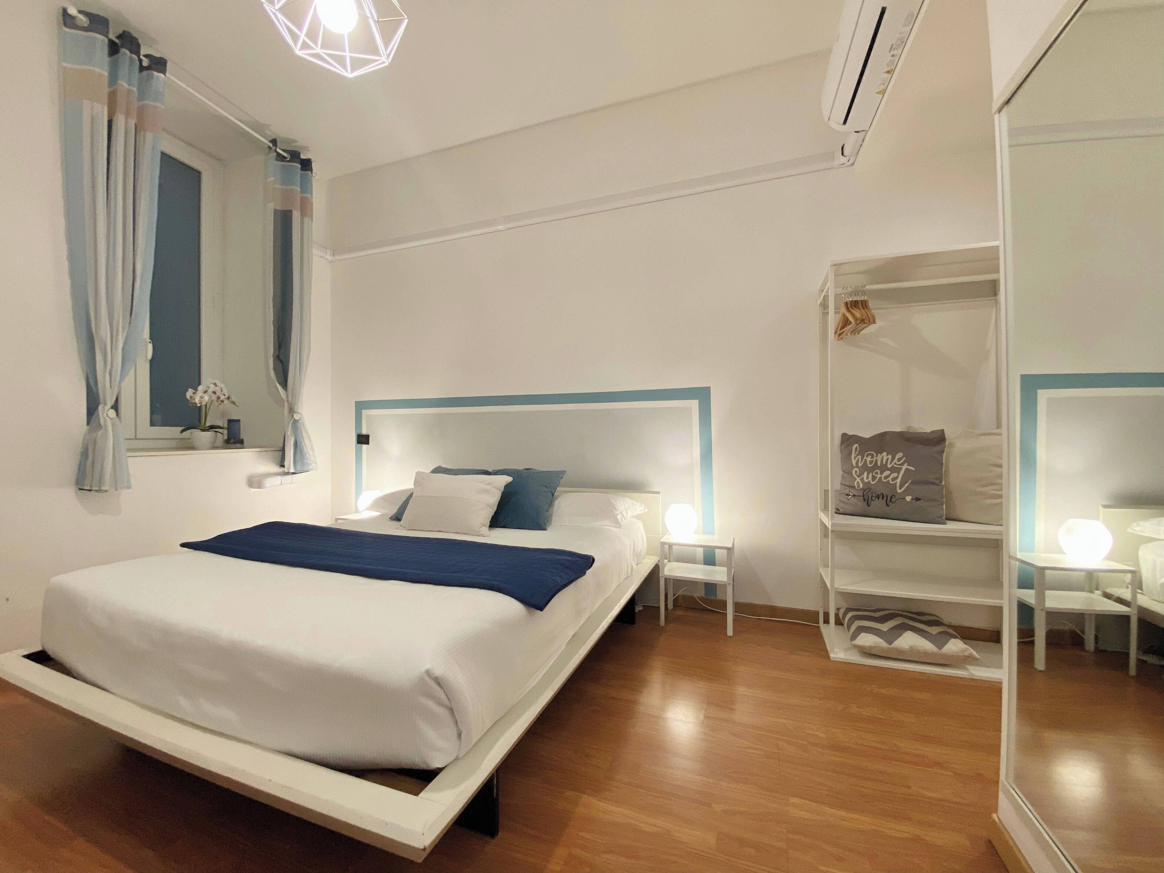 A modern bedroom with a bed, bedside tables, a nightstand, a mirror, and a window with curtains.