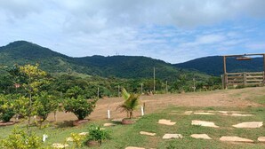Un paysage rural avec un chemin de terre, des arbres dispersés et une structure en bois.