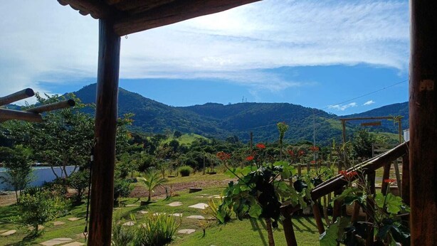 Un jardin agrémenté d’une pergola en bois, d’un sentier et offrant une vue sur les montagnes.