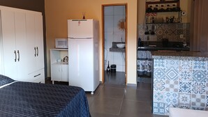 Une cuisine compacte équipée d’un four à micro-ondes, d’un réfrigérateur et d’un plan de travail recouvert de carreaux.