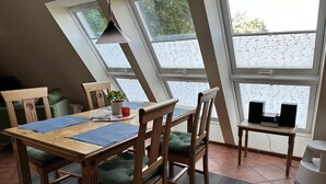 Un comedor con una mesa de madera, sillas y una mesita auxiliar con altavoces.