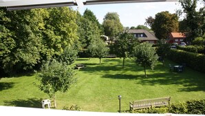 Vista de un jardín bien cuidado con césped, árboles y mobiliario de exterior.