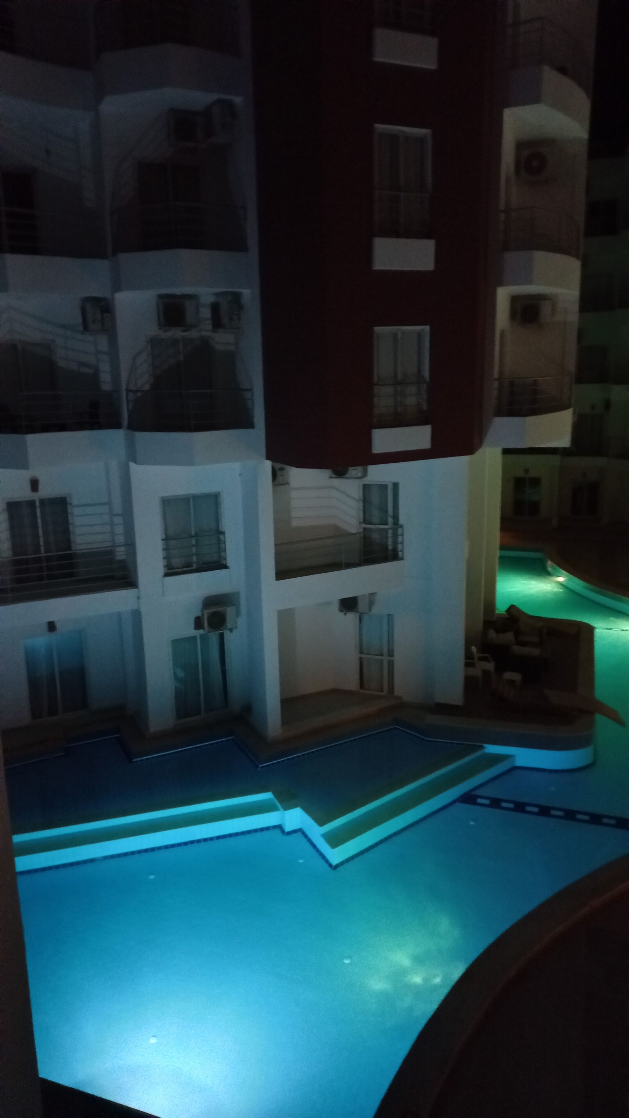 A multi-story building with balconies and a swimming pool area.