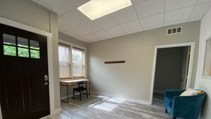 A room with a desk, chair, and a blue armchair. - 2 bedroom Budget Suite. Open floor plan (Mattoon)