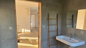Une salle de bain avec un lavabo blanc, une échelle en bois et un miroir au mur.