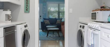 A compact kitchen with built-in appliances, a dining area with a ceiling fan, and a view into a living room with a couch and a coffee table.