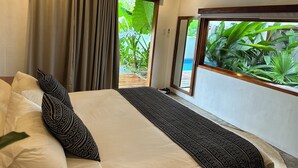 Een slaapkamer met een bed, gordijnen, een raam met uitzicht op groen en een airconditioning.