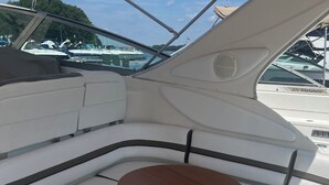 A boat's interior with a cushioned seating area, a small table, and a storage compartment.