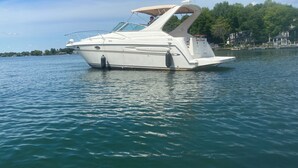 A white motorboat named "AXUM" on calm water.